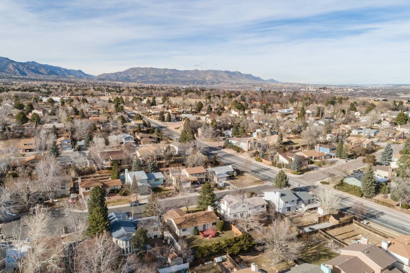 A residential area with houses, roads, and mountains in the background.