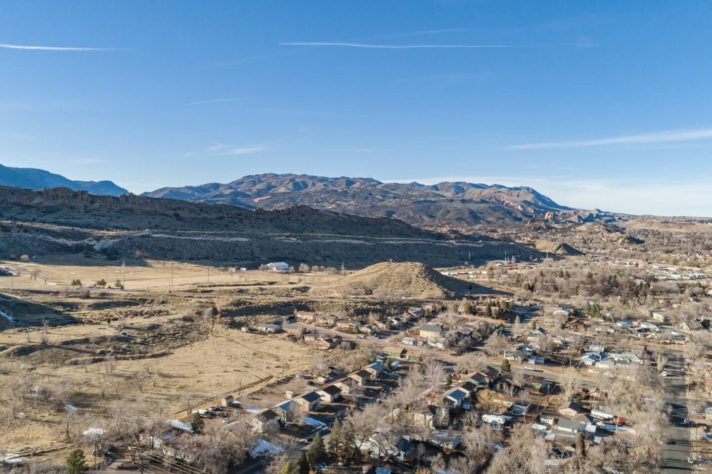 Un pueblo rural con casas y una cadena montañosa al fondo.