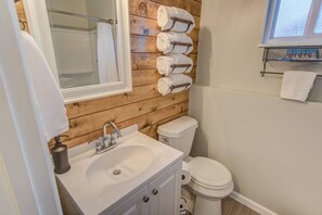 A bathroom with a wooden wall, a sink, a toilet, and a towel rack with multiple towels. - Westside Value Parks & Trails Close to it all (Colorado Springs)