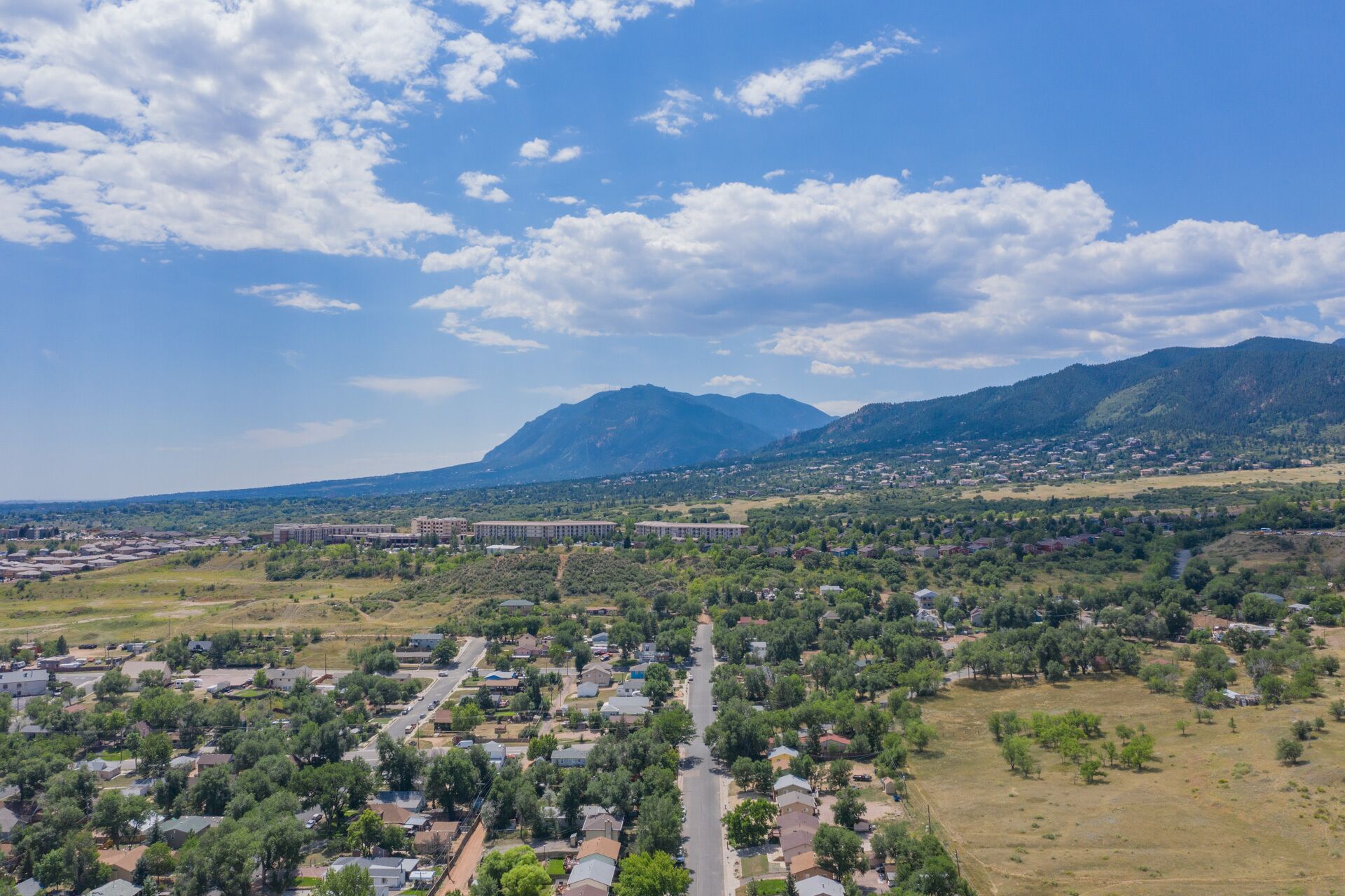 A residential area with houses, a main road, and a mountain in the background.