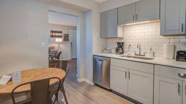 A modern kitchen with grey cabinets, a dishwasher, and a coffee maker. - Westside Value Parks & Trails Close to it all (Colorado Springs)