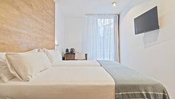 A hotel room with a bed, a desk, a chair, a television, and a window with curtains.