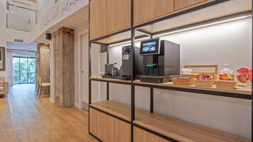 A modern hotel lobby with a coffee machine, a digital screen, and a reception desk.