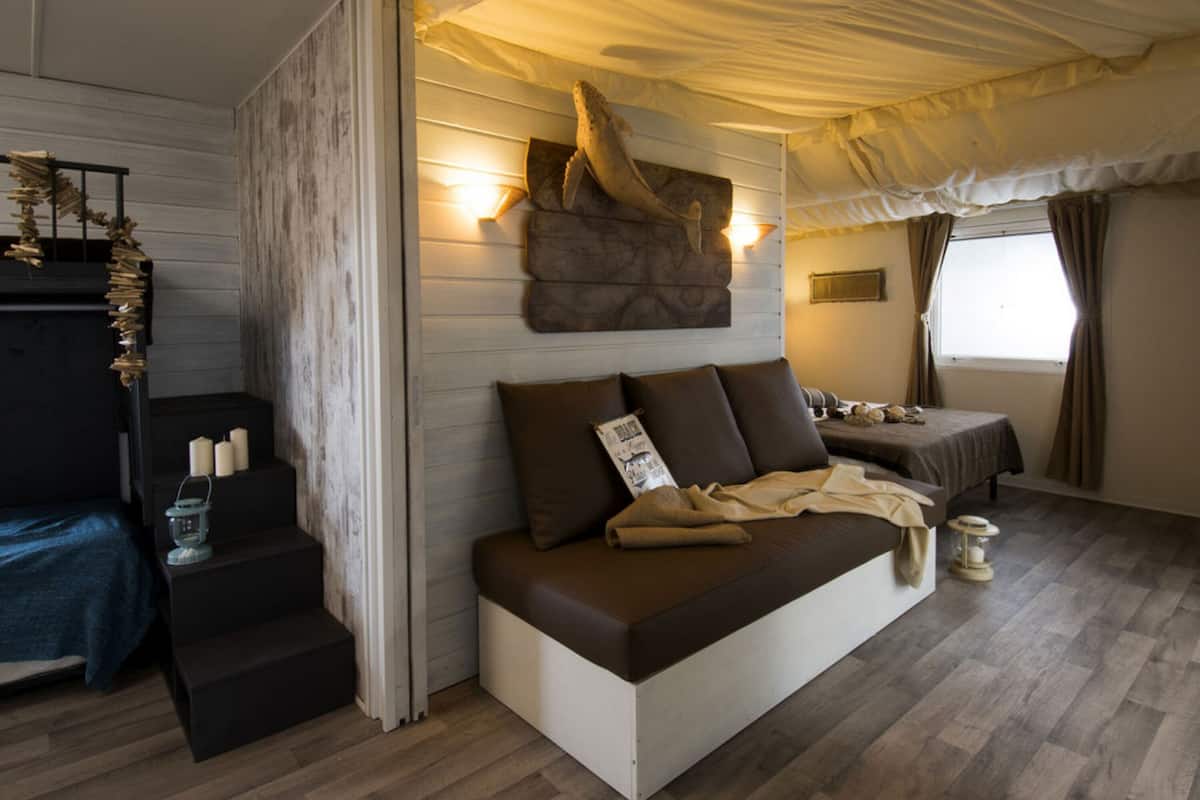 A cozy room with a bed, a small table with candles, and a wall-mounted sculpture.