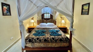 A bed with a canopy, two bedside lamps, and a patterned bedspread. - Zen Villa # 1 -  Three bedroom Luxury Villa with Private Garden -Playa Chiquita (Puerto Viejo de Talamanca)