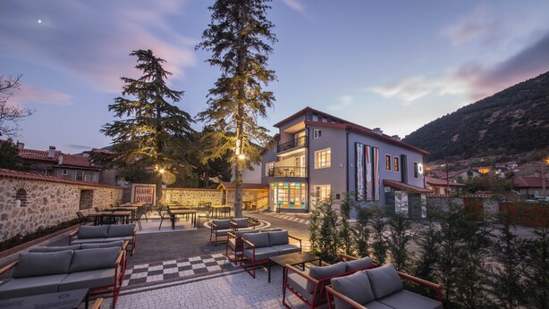 A hotel with outdoor seating, a checkered floor, and a view of the surrounding area.
