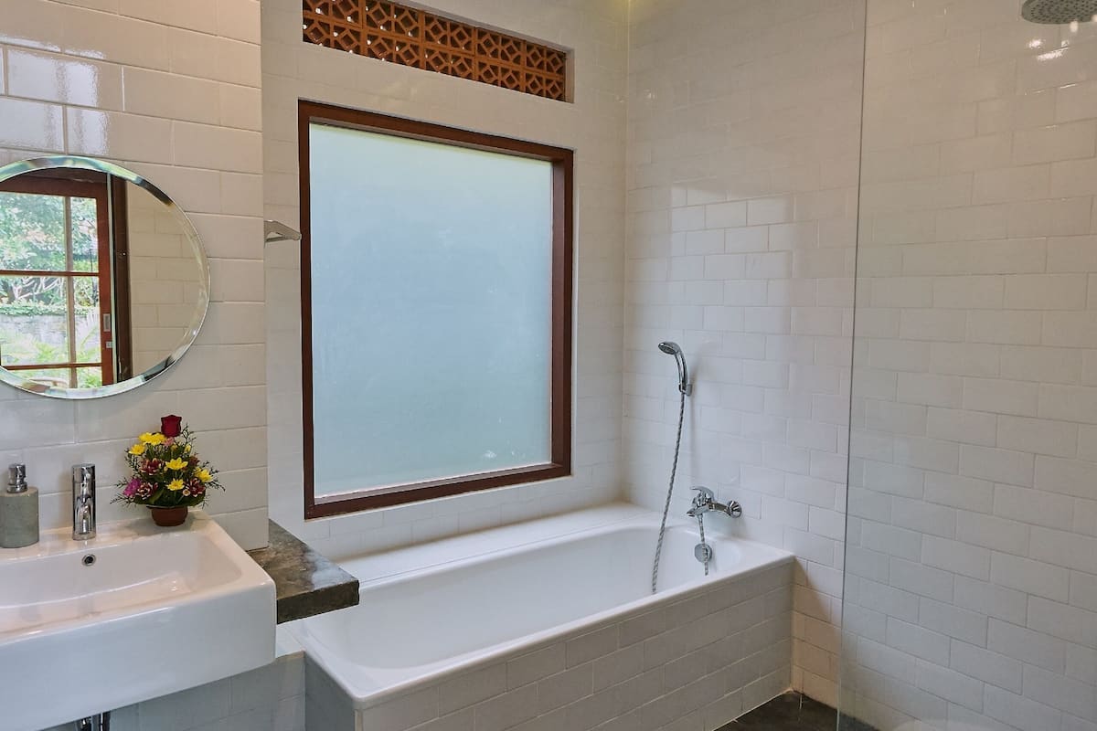 A modern bathroom with a white sink, a large mirror, a bathtub, and a toilet.