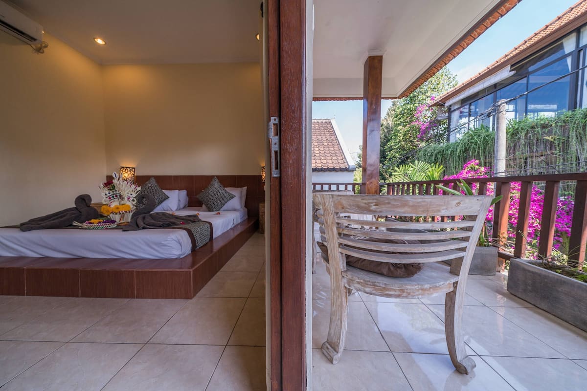 A bedroom with a bed, bedside table, and a balcony with a chair.