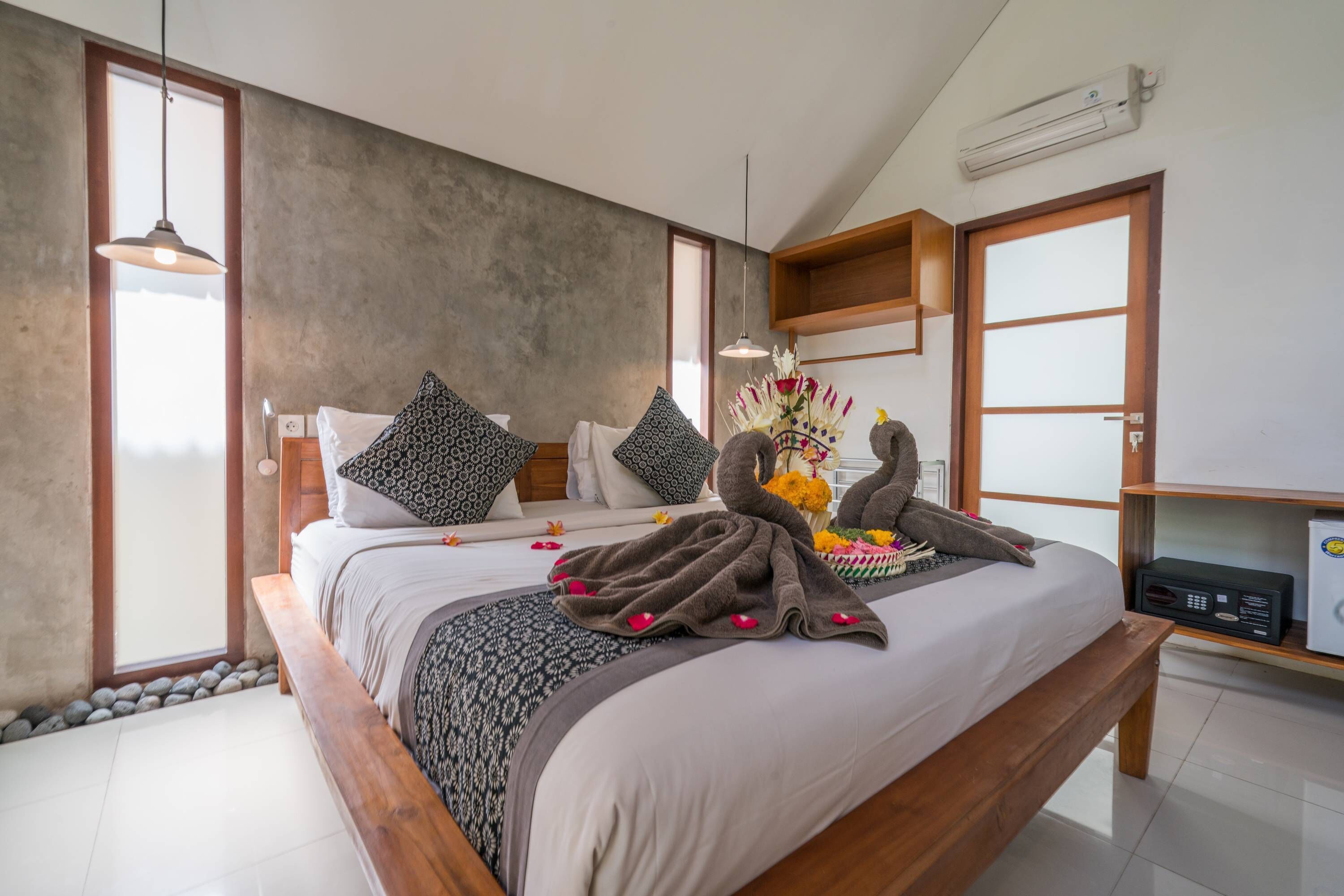A modern bedroom with a large bed, a wooden bench, a small table with a radio, and a decorative headpiece on the bed.