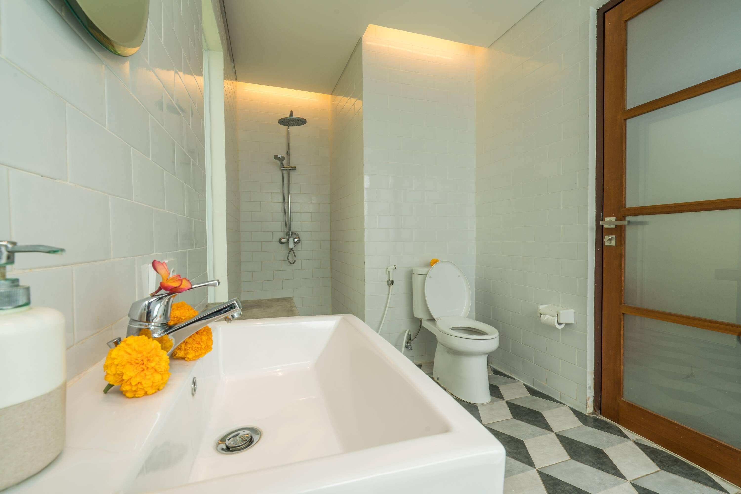 A bathroom with a white sink, a shower, and a toilet.