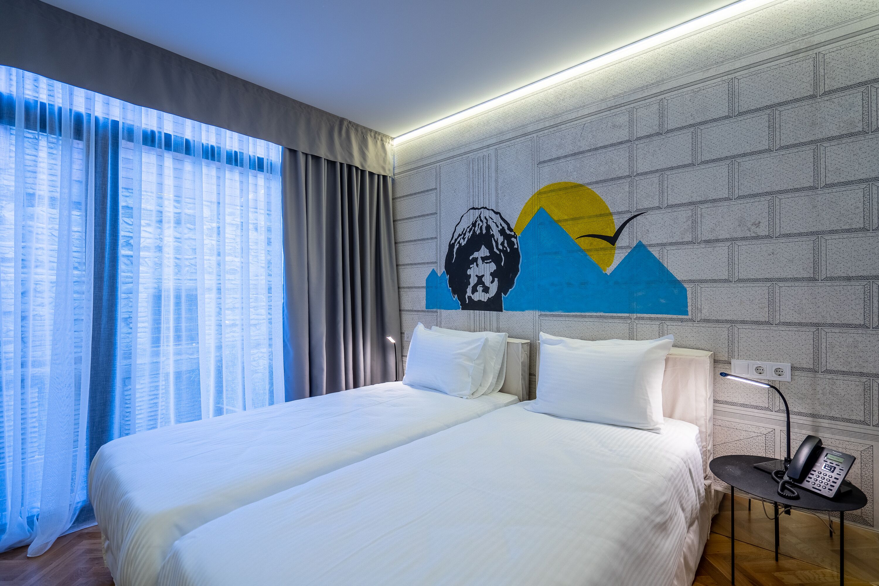 Una habitación de hotel con una cama grande, una mesita de noche con lámpara y una obra de arte colgada en la pared.