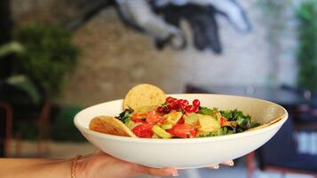 Un bol de salade avec une chips de tortilla, présenté devant un mur orné d’une fresque.