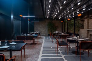 Un restaurante con mesas y sillas, un muro de ladrillo y luces colgantes.