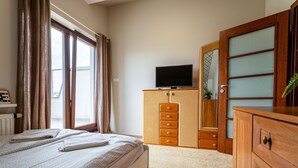 A bedroom with a bed, a wooden dresser, a television on top, and a window with curtains. - Victus Apartamenty - Cadena 1 (Sopot)