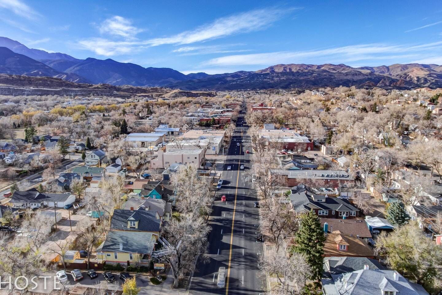 Une ville dont la rue principale est bordée de maisons et d’immeubles, et qui est entourée de montagnes.
