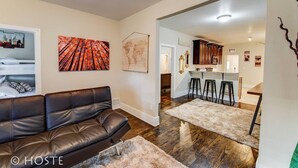 A living room with a leather couch, a world map, and a vibrant abstract painting.