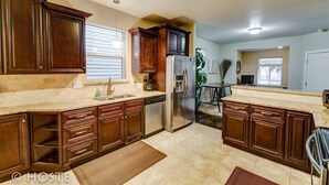 A kitchen with wooden cabinets, a stainless steel refrigerator, and a granite countertop.