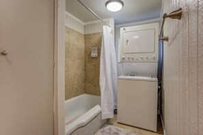 A compact bathroom with a shower, a toilet, and a small washing machine.