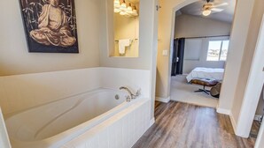 A modern bathroom with a large bathtub, a mirror, and a painting on the wall. - 3BR AF Academy Pet-friendly (Colorado Springs)