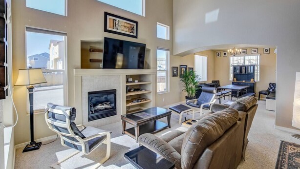 A spacious living room with a fireplace, a large flat-screen TV, and comfortable seating. - 3BR AF Academy Pet-friendly (Colorado Springs)