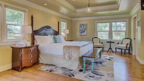 A spacious bedroom with a large bed, a wooden dresser, and a bench. There are two chairs and a small table in the corner. - 5BR Mnt Viewsdowntown Luxuryfirepit & RV Parking (Colorado Springs)