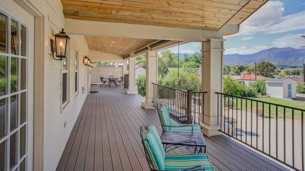 A covered porch with wooden flooring, outdoor seating, and a view of the surrounding landscape. - 5BR Mnt Viewsdowntown Luxuryfirepit & RV Parking (Colorado Springs)