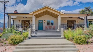 A two-story building with a central entrance, a covered porch, and a staircase leading to the entrance. - 5BR Mnt Viewsdowntown Luxuryfirepit & RV Parking (Colorado Springs)