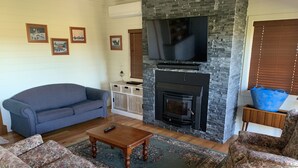 A living room with a fireplace, a sofa, a coffee table, and a TV. - Peppergrove Cottage (Berry)