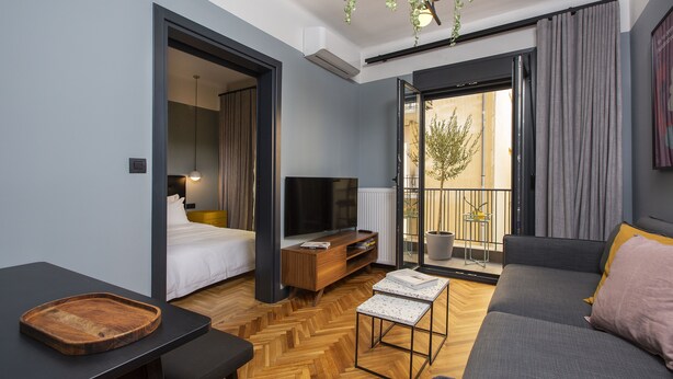 Ein modernes Wohnzimmer mit einer Couch, einem Esstisch, einem Fernseher und einem Balkon mit Blick.