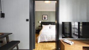 Ein Hotelzimmer mit Bett, Schreibtisch, Bank, Fernseher und einem gerahmten Bild an der Wand.