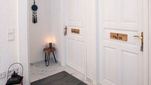 A hallway with white doors, a dark rug, a small table with a candle, and a lantern. - Blue Mountain Guesthouse "Freya” (Arachova)