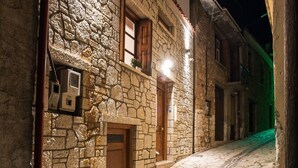 A narrow cobblestone street flanked by stone buildings with wooden doors and windows, illuminated by warm lighting. - Blue Mountain Guesthouse "Freya” (Arachova)