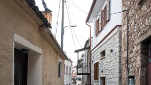 A narrow cobblestone street flanked by traditional stone buildings with wooden shutters and a visible power line. - Blue Mountain Guesthouse "Freya” (Arachova)