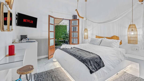 A bedroom with a bed, bedside table, TV, and a view of the outdoors. - Blue Mountain Guesthouse "Freya” (Arachova)