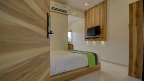 Une chambre à coucher avec un lit en bois, un téléviseur fixé au mur et un appareil de climatisation.