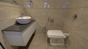 Une salle de bain moderne avec un lavabo blanc, des toilettes et une douche.