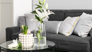 A modern living room with a grey sofa, a round mirror, and a glass coffee table with decorative items. - Sodispar Szpitalna Old Town Apartments (Kraków)