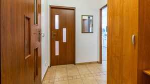 Un pasillo con puertas de madera, suelo de baldosas y un espejo en la pared.