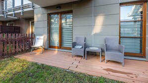 Un área de estar al aire libre con sillas de mimbre, una pequeña mesa, un letrero y una terraza de madera.