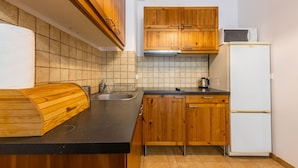 Una cocina con armarios de madera, encimera negra, refrigerador blanco y salpicadero de azulejos.