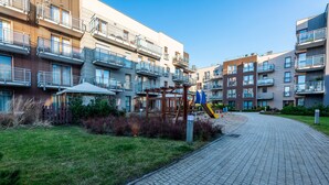 Un edificio residencial con varios balcones, un parque infantil y un camino pavimentado.