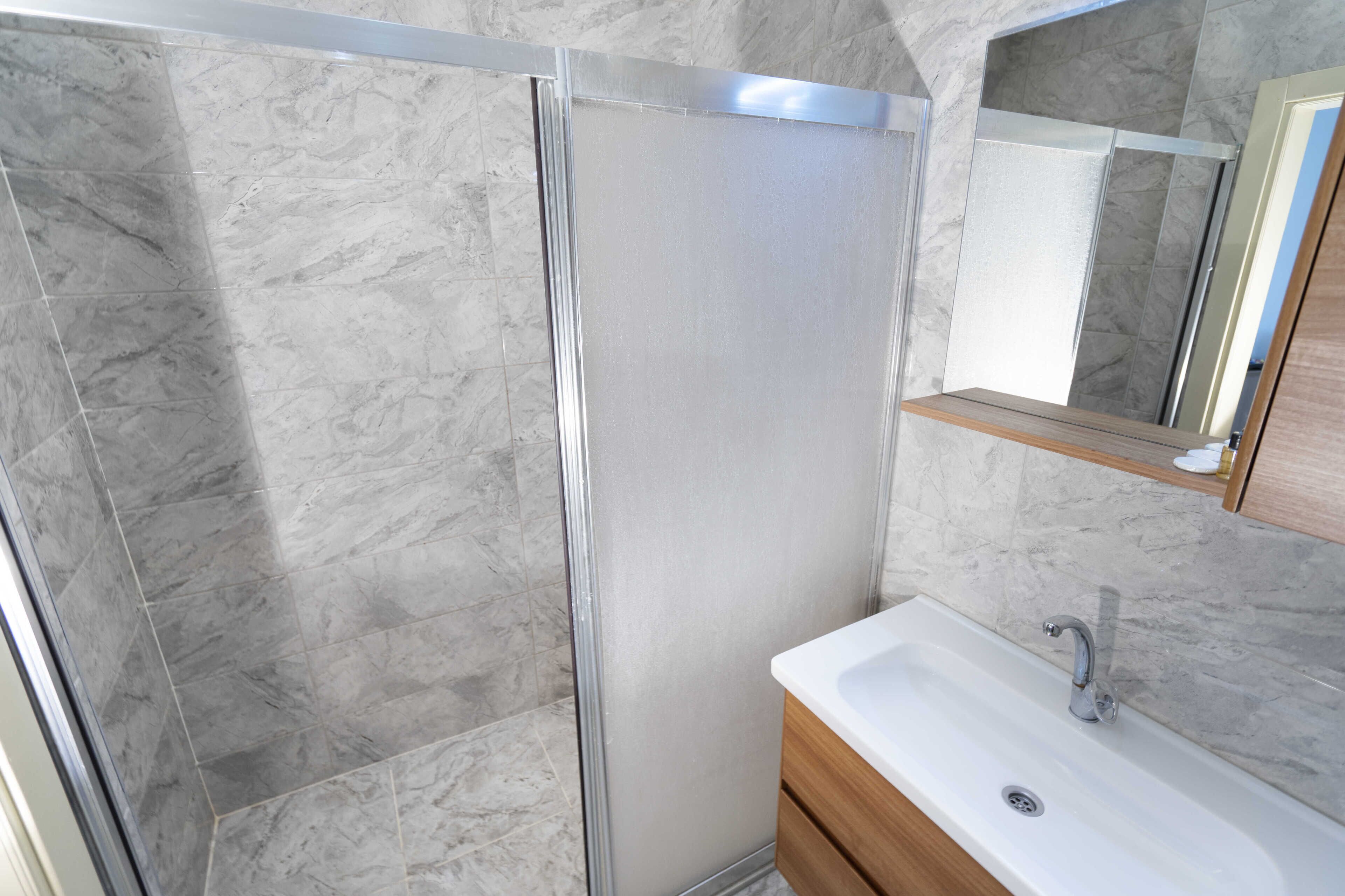 Un baño con ducha, lavamanos y espejo.