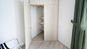 Un vestidor con puertas de madera, un perchero metálico y una silla metálica.