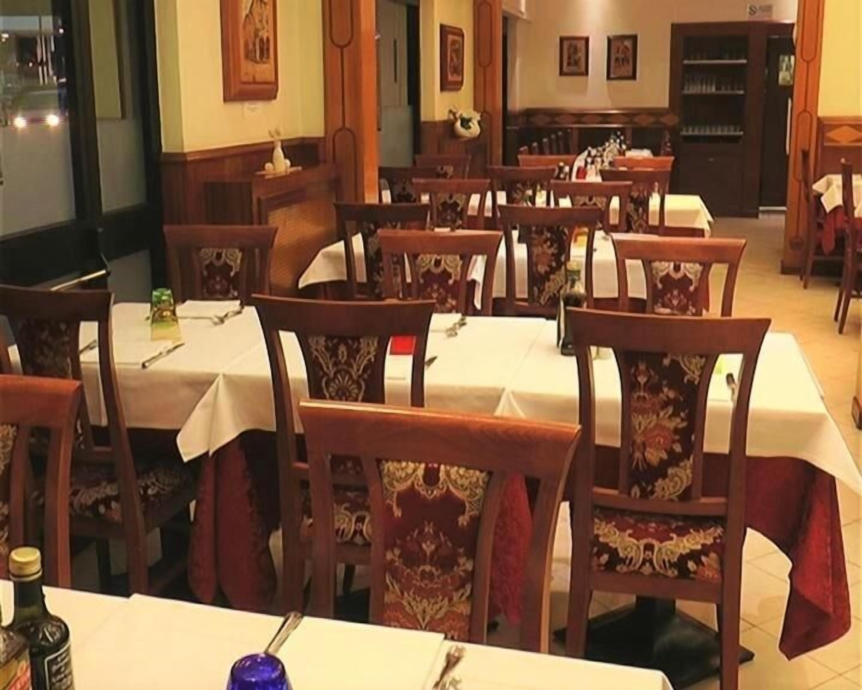 A dining area with multiple tables and chairs, each covered with a white tablecloth.