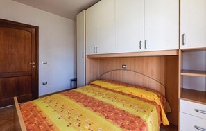 A bedroom with a bed, wooden wardrobe, and a small desk.