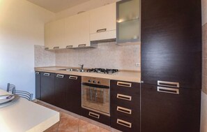 A modern kitchen with dark cabinetry, a gas stove, and a built-in oven.
