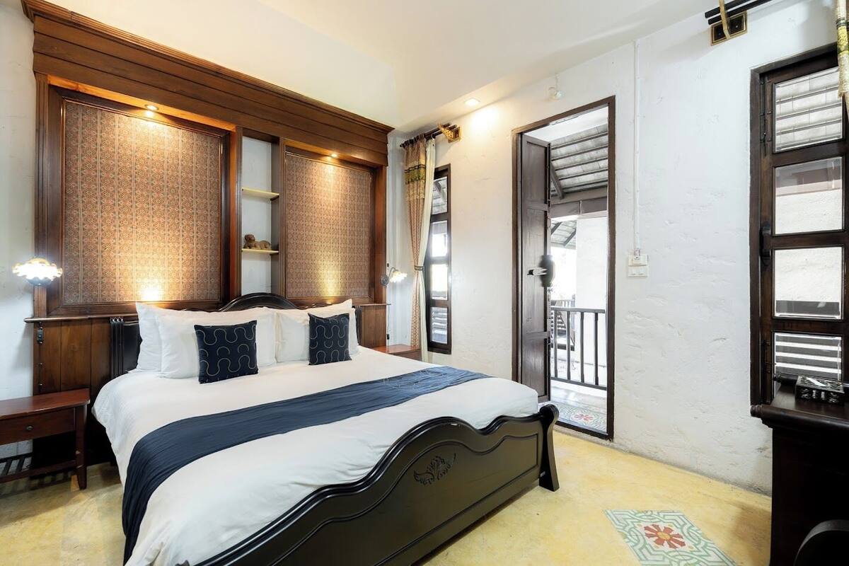 Un dormitorio con cama, mesitas de noche, armario, espejo y puerta al balcón.