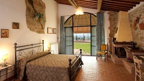 Un dormitorio con cama, chimenea de piedra y vistas al exterior.