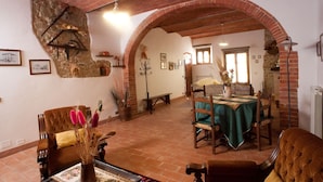 Una habitación rústica con comedor, chimenea y pared de piedra.