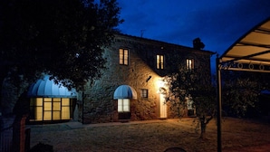 Un edificio de piedra con dos ventanas arqueadas y un patio cubierto.
